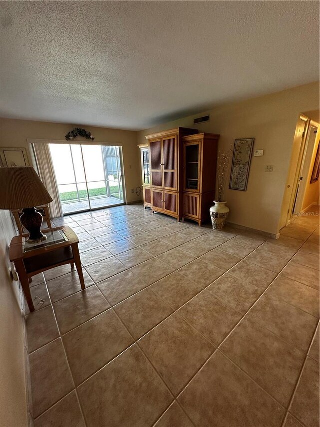 unfurnished living room featuring tile patterned flooring and a textured ceiling