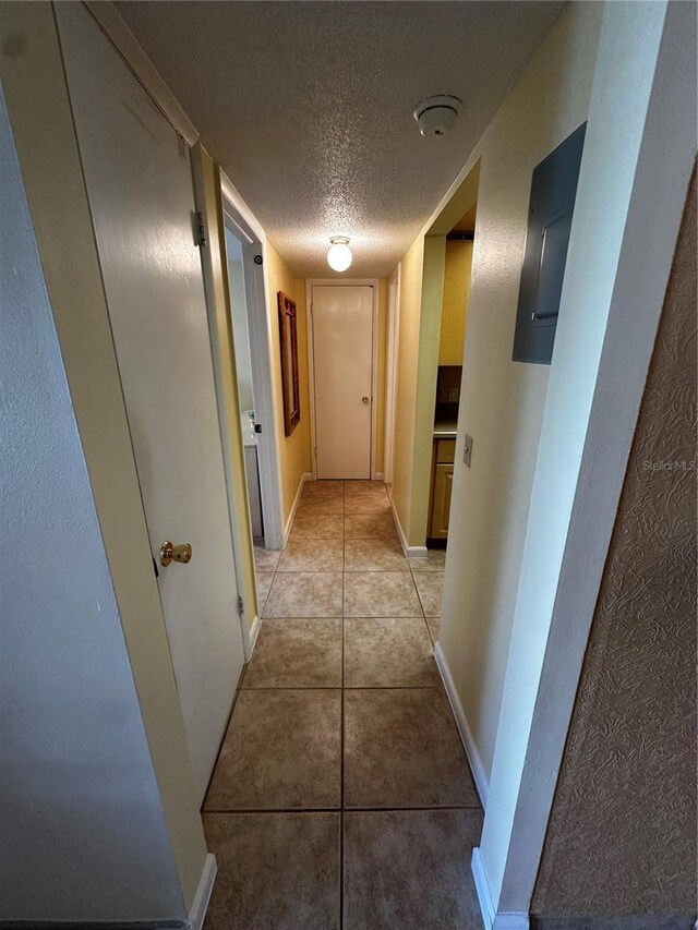 corridor with light tile patterned floors and a textured ceiling