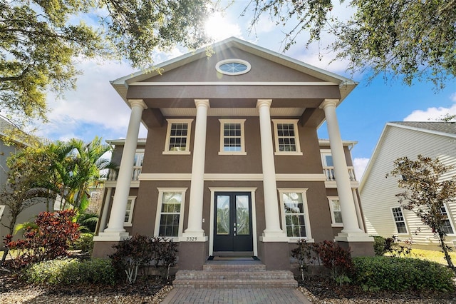 neoclassical home featuring french doors and stucco siding