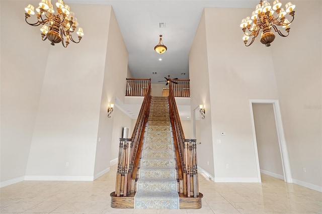 stairs featuring baseboards, a towering ceiling, visible vents, and an inviting chandelier