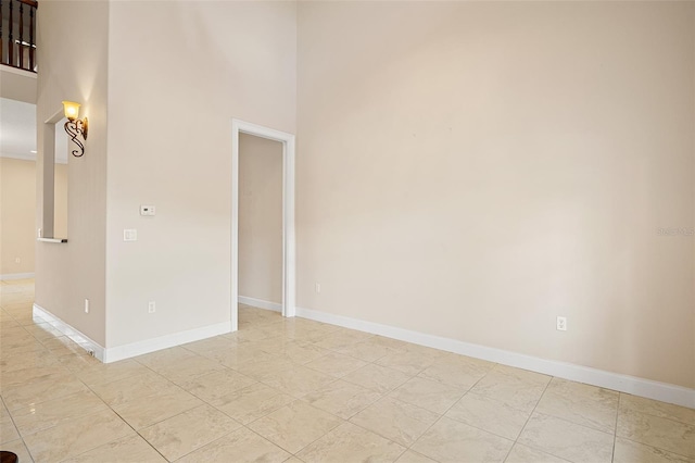 unfurnished room featuring a towering ceiling and baseboards