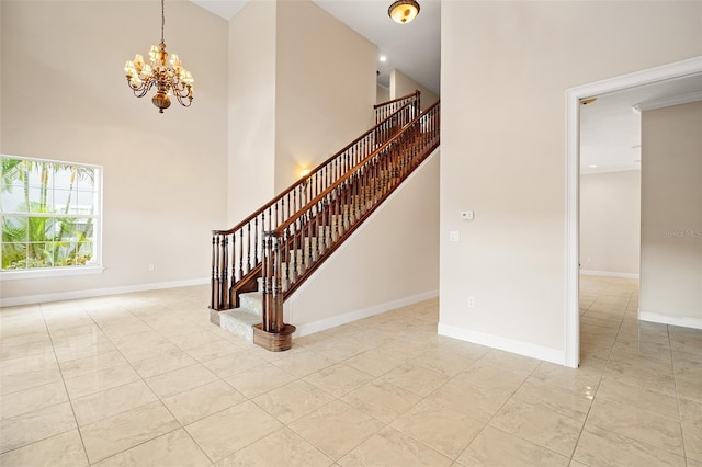 staircase with a notable chandelier, a high ceiling, and baseboards