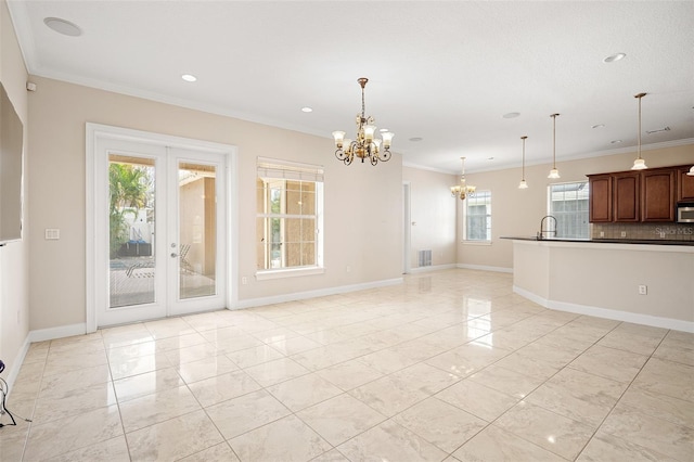 unfurnished living room featuring a chandelier, ornamental molding, visible vents, and baseboards