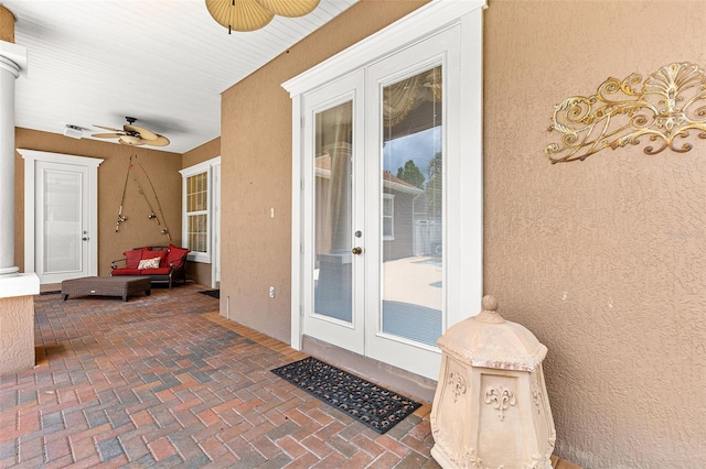 view of exterior entry with stucco siding, ceiling fan, a patio, and french doors