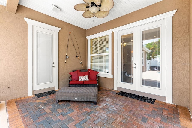 view of exterior entry featuring ceiling fan, french doors, a patio area, and stucco siding