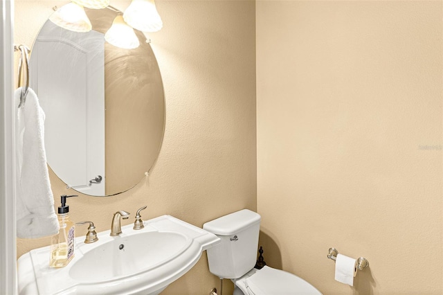 bathroom featuring a textured wall, a sink, and toilet