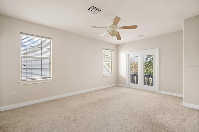 empty room with light carpet, ceiling fan, visible vents, and baseboards