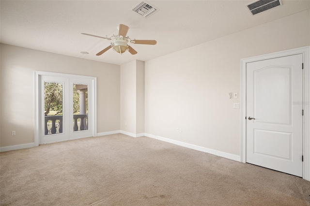 carpeted empty room featuring baseboards, visible vents, and a ceiling fan