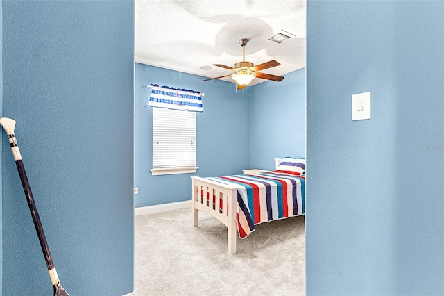 carpeted bedroom featuring a textured ceiling, a textured wall, visible vents, baseboards, and a ceiling fan