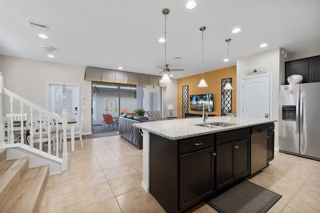 kitchen featuring sink, light stone counters, decorative light fixtures, a center island with sink, and stainless steel appliances