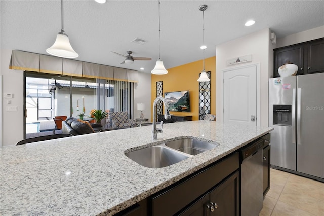 kitchen featuring light stone counters, appliances with stainless steel finishes, decorative light fixtures, and sink