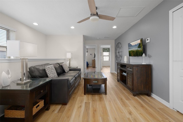 living room with a textured ceiling, light hardwood / wood-style floors, and ceiling fan