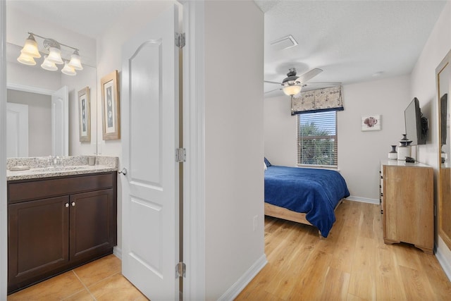 bedroom with sink, light hardwood / wood-style floors, a textured ceiling, and ceiling fan