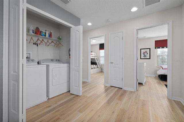 clothes washing area with light hardwood / wood-style floors, independent washer and dryer, and a textured ceiling