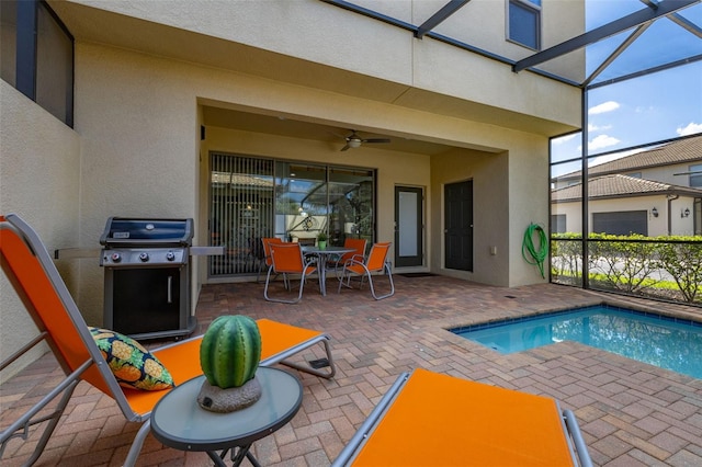 view of swimming pool with ceiling fan, grilling area, a lanai, and a patio