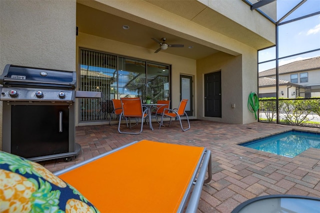 view of pool featuring ceiling fan, area for grilling, a patio, and glass enclosure