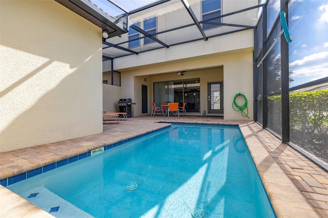 view of swimming pool with a patio, area for grilling, and glass enclosure