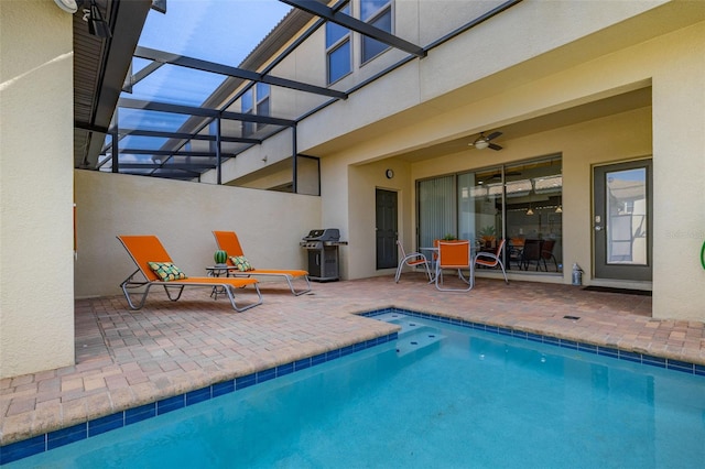 view of pool featuring ceiling fan, area for grilling, glass enclosure, and a patio