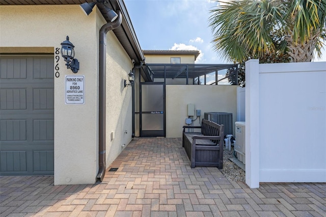 view of patio featuring a garage, a lanai, and central air condition unit