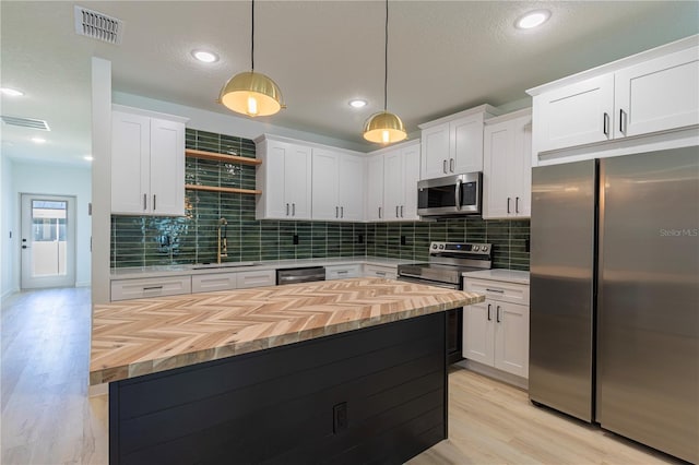 kitchen featuring a sink, visible vents, white cabinetry, appliances with stainless steel finishes, and pendant lighting