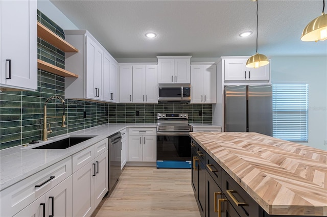 kitchen with white cabinets, pendant lighting, and stainless steel appliances