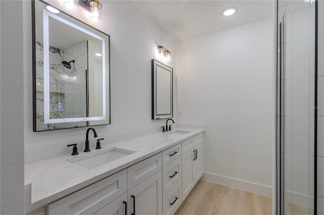 bathroom featuring wood finished floors, a sink, a tile shower, and double vanity