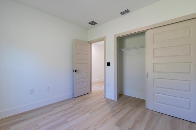 unfurnished bedroom featuring baseboards, a closet, visible vents, and light wood-style floors