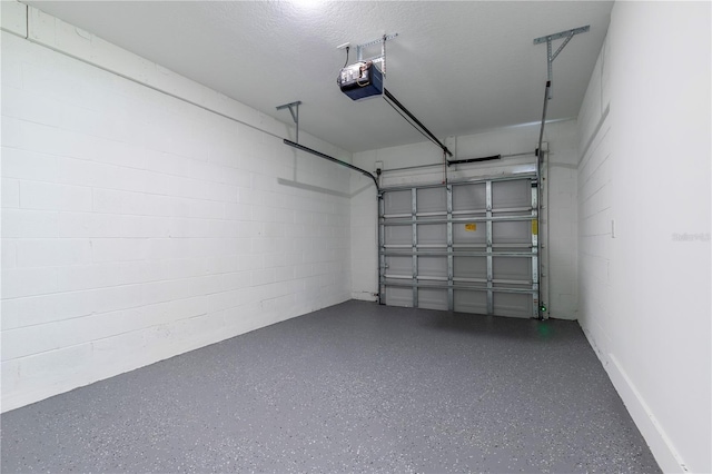 garage featuring concrete block wall and a garage door opener