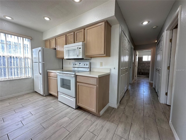 kitchen featuring a healthy amount of sunlight, light brown cabinets, and white appliances