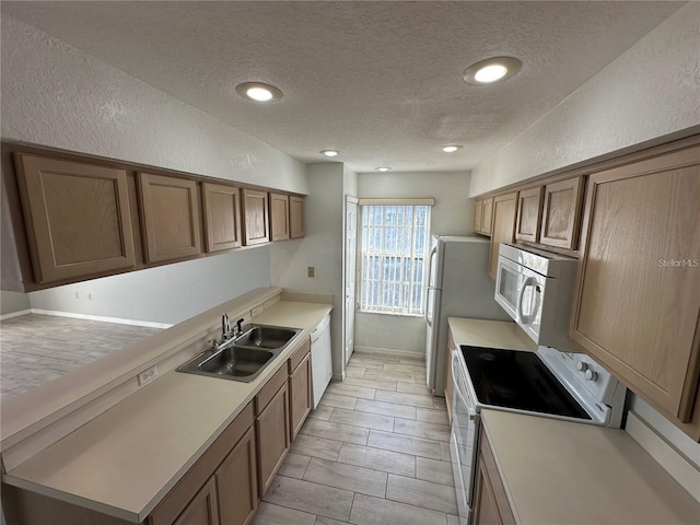 kitchen featuring white appliances, sink, and a textured ceiling