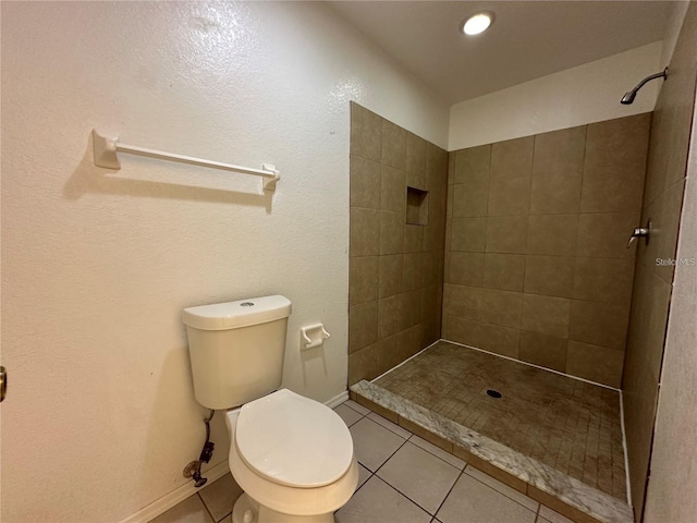 bathroom with tile patterned floors, toilet, and a tile shower