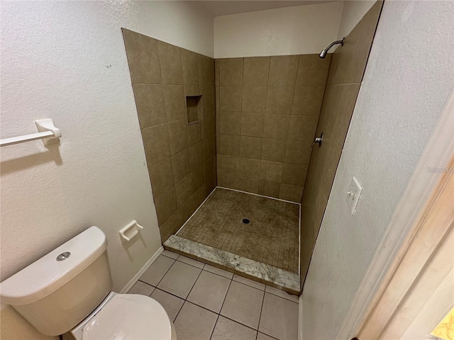 bathroom with tile patterned flooring, toilet, and tiled shower