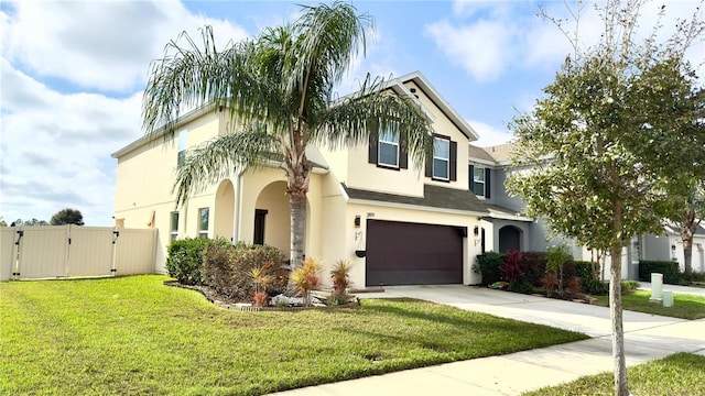 view of front of house featuring a front lawn, concrete driveway, stucco siding, an attached garage, and a gate