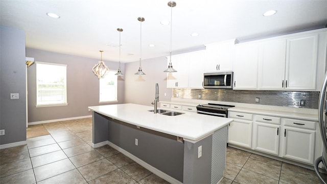 kitchen with backsplash, a center island with sink, light countertops, stainless steel appliances, and a sink