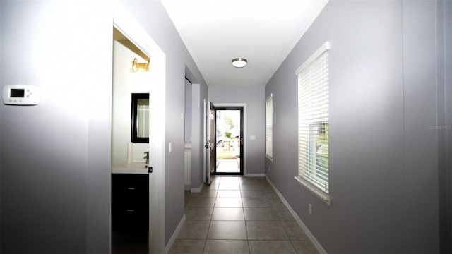 doorway to outside with light tile patterned floors and baseboards