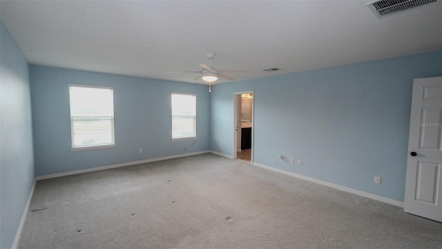 unfurnished room with visible vents, baseboards, light colored carpet, and ceiling fan