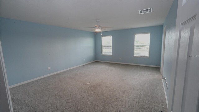 carpeted empty room with visible vents, baseboards, and ceiling fan