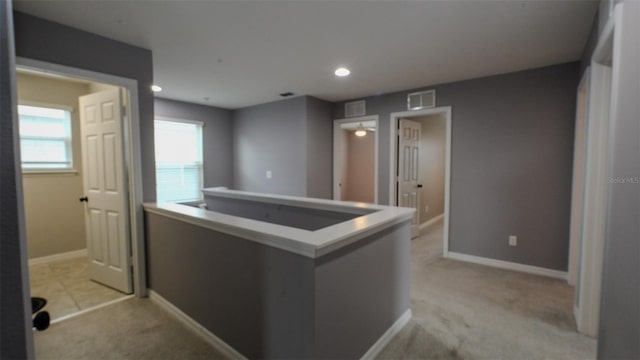 interior space featuring light colored carpet, visible vents, and baseboards