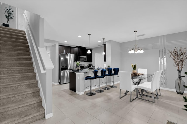 kitchen featuring light tile patterned floors, stainless steel appliances, a kitchen breakfast bar, light stone countertops, and a chandelier