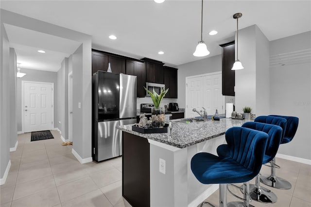 kitchen featuring sink, light stone counters, decorative light fixtures, kitchen peninsula, and stainless steel appliances