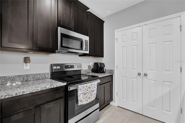 kitchen with light stone counters, dark brown cabinets, and stainless steel appliances