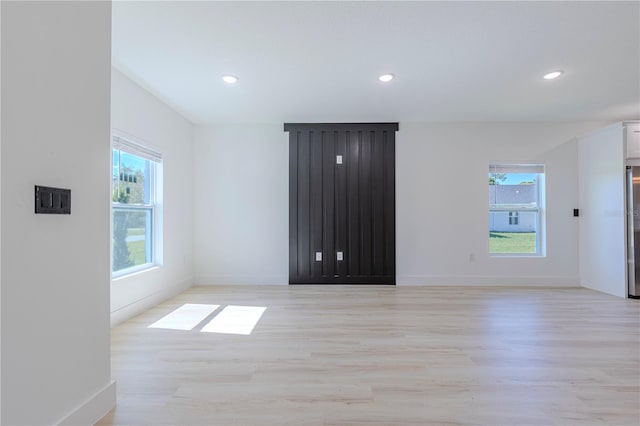 unfurnished room featuring baseboards, light wood-type flooring, plenty of natural light, and recessed lighting