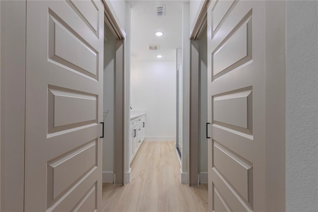 hallway with baseboards, light wood finished floors, visible vents, and recessed lighting