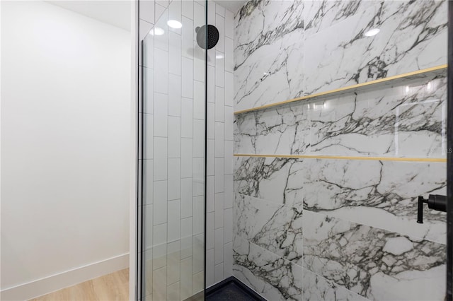 full bath with baseboards, a tile shower, and wood finished floors