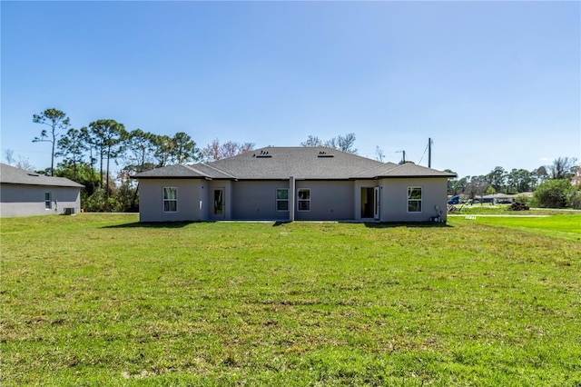 rear view of property featuring a lawn and stucco siding