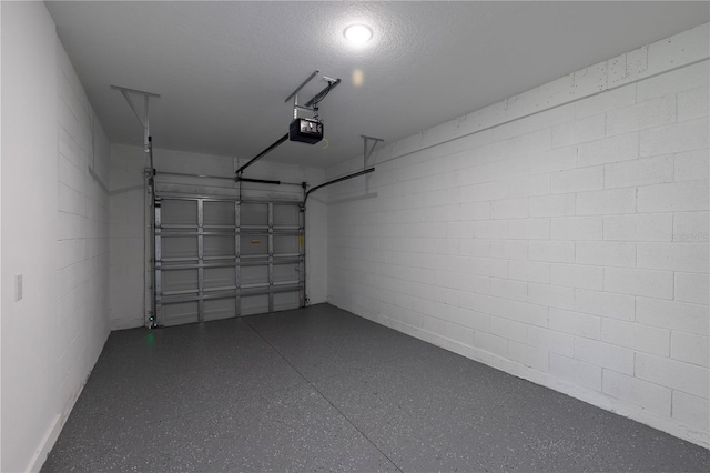 garage featuring a garage door opener and concrete block wall