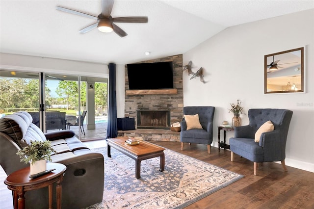 living room with vaulted ceiling, a stone fireplace, wood-type flooring, and ceiling fan