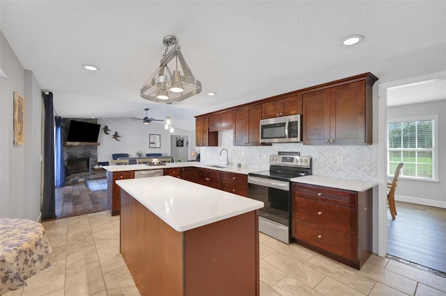 kitchen featuring pendant lighting, sink, decorative backsplash, kitchen peninsula, and stainless steel appliances