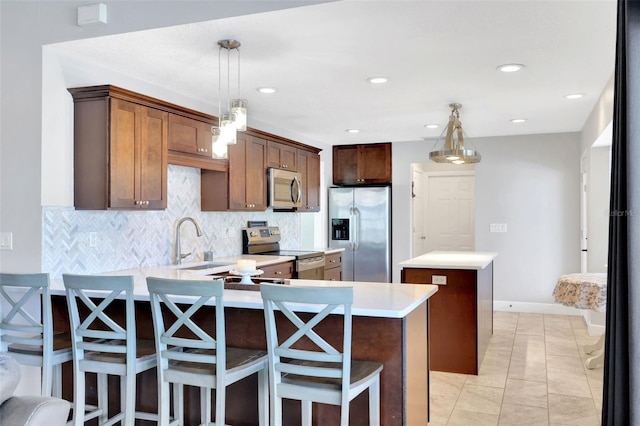 kitchen with hanging light fixtures, appliances with stainless steel finishes, sink, and a kitchen bar