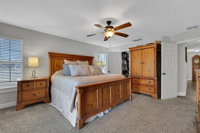 bedroom with multiple windows, light colored carpet, and a textured ceiling